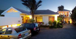 dos autos estacionados en un estacionamiento frente a una casa en Algoa Guest House Summerstrand, en Port Elizabeth