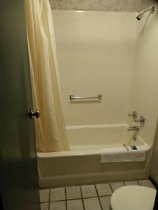 a bathroom with a bath tub and a toilet at Kensington Inn - Howell in Howell