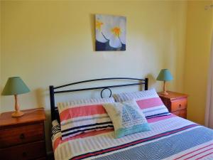 a bedroom with a bed with striped pillows and two lamps at Donlan's Delight in Mollymook