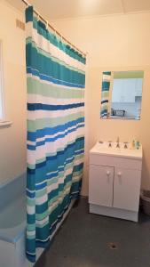a bathroom with a striped shower curtain and a sink at Donlan's Delight in Mollymook
