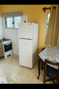 um frigorífico branco numa cozinha com uma mesa em La escondida em Mercedes