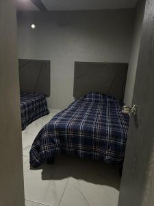 um quarto com uma cama com um cobertor xadrez azul em Residencia en Apodaca Nuevo León em Monterrey