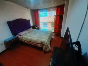 a small bedroom with a bed and a television at Siren's House in Cusco