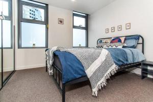 a bedroom with a bed with a blue comforter and windows at 2 Bed Apt with CAR Parking in SouthYarra（TF150221） in Melbourne