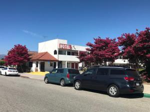 dos coches estacionados en el lado de una calle frente a un hotel en Eunice Plaza Motel, en El Monte