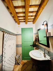 a bathroom with a sink and a green door at Cortile Padre Vincenzo in Erice