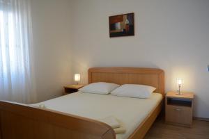 a bedroom with a bed with white sheets and two lamps at Apartment Roby in Senj