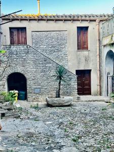 a stone building with a palm tree in front of it at Cortile Padre Vincenzo in Erice