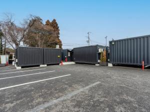 a row of shipping containers in a parking lot at HOTEL R9 The Yard Mokainter in Mooka