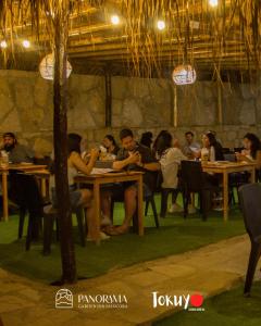 un grupo de personas sentadas en mesas en un restaurante en Panorama garden inn, en Máncora
