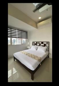 1 dormitorio con 1 cama grande con sábanas blancas y ventana en Calyx Residences, 18H, en Cebú