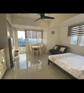 1 dormitorio con cama, mesa y ventilador de techo en Calyx Residences, 18H, en Cebú