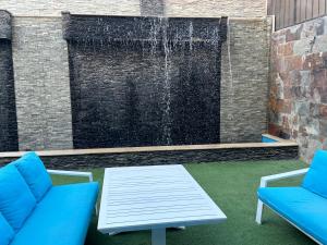 a fountain with two blue chairs and a table at Trio villa with falls in compound فلا بحديقة كبيره وشلالات صناعية in Sheikh Zayed