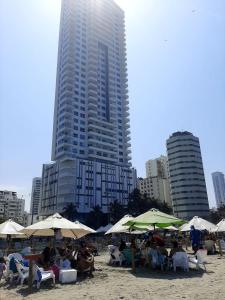un grupo de personas sentadas bajo sombrillas en una playa en Apartamento 3404 Palmetto Beach Frente a la playa, en Cartagena de Indias