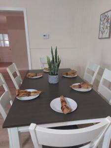 ein schwarzer Tisch mit weißen Stühlen und Platten sowie eine Pflanze in der Unterkunft Rustic Redlion Home 