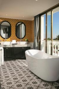 會安的住宿－Grand Sunrise Palace Hoi An，带浴缸、两个盥洗盆和镜子的浴室
