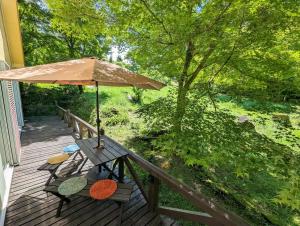 a picnic table with an umbrella on a deck at 星空に包まれる 森の隠れ家　Amrita Lodge ~stay & retreat~ in Kirishima