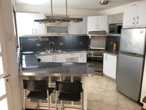 a kitchen with white cabinets and a black counter top at Casa frente a la playa con wifi in Tucacas