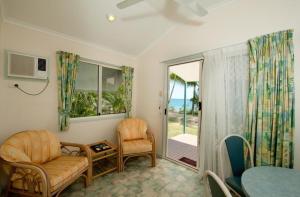 een woonkamer met een stoel, een tafel en een raam bij Ellis Beach Oceanfront Holiday Park in Palm Cove