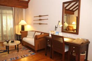 a living room with a couch and a desk and a mirror at The Oberoi Beach Resort, Lombok in Tanjung
