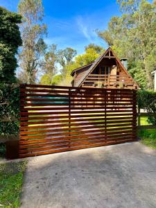 una valla de madera con una casa detrás en Casa Estilo Cabaña, Bosque Peralta Ramos en Mar del Plata