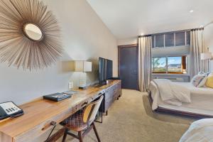 1 dormitorio con escritorio, 1 cama y espejo en Desert Rose Resort & Cabins, en Bluff
