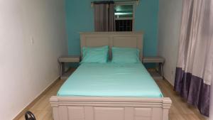 Cette petite chambre comprend un lit avec des draps bleus. dans l'établissement Tropical Hotel & guest house, à Cap-Haïtien