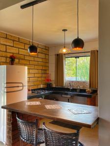a kitchen with a wooden table and a refrigerator at Pousada & Camping Nativos dos Canyons in Praia Grande