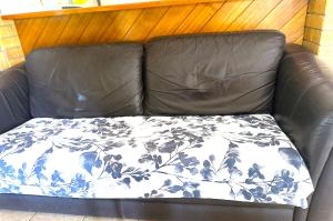 - un canapé en cuir noir avec couverture dans l'établissement Cosy holiday entire unit 1, à Caloundra West