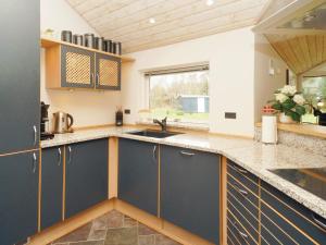 a kitchen with blue cabinets and a wooden ceiling at 10 person holiday home in R dby in Rødby
