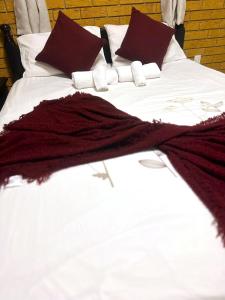 uma cama com lençóis brancos e almofadas bordeaux em Cosy holiday entire unit 1 em Caloundra West