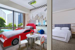 a bedroom with two beds and a table with a car on the wall at Four Points by Sheraton Surabaya, Pakuwon Indah in Surabaya