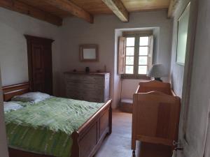 een slaapkamer met een bed, een dressoir en een raam bij Maison de caractère au coeur de la corse rurale in Calacuccia
