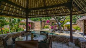 an outdoor patio with a table and chairs and a pool at The Oberoi Beach Resort, Lombok in Tanjung