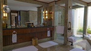 a bathroom with a shower and a sink and a mirror at The Oberoi Beach Resort, Lombok in Tanjung
