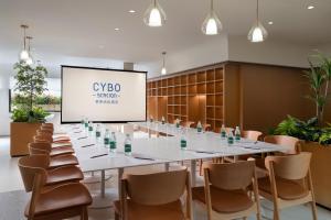 a conference room with a long table and chairs and a screen at CYBO Station Luohu Shenzhen in Shenzhen