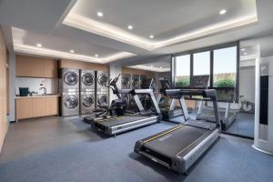a gym with treadmills elliptical machines and washing machines at CYBO Station Luohu Shenzhen in Shenzhen