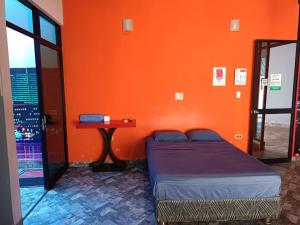 um quarto com uma parede laranja com uma cama e uma mesa em Hospedaje Vegas em Tarapoto