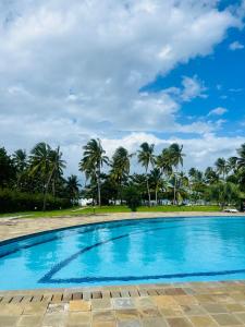 una piscina con palmeras en el fondo en Beachfront Studio-Waves & Wanderlust Haven, en Mombasa