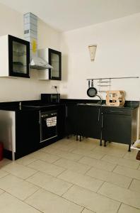 a kitchen with black cabinets and a tile floor at Beachfront Studio-Waves & Wanderlust Haven in Mombasa