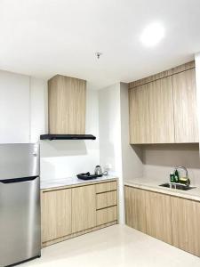 a kitchen with wooden cabinets and a stainless steel refrigerator at Formosa Residence Nagoya, 2 Bedroom, Batam City in Nagoya