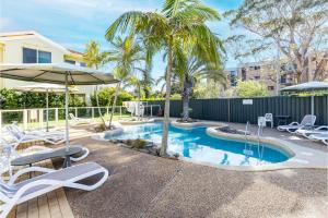 una piscina con sedie, ombrellone e palme di Martys 7 2 Intrepid Cl - pool , air con , Wi-Fi and linen a Nelson Bay