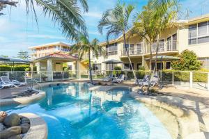 una piscina di fronte a un edificio con palme di Martys 7 2 Intrepid Cl - pool , air con , Wi-Fi and linen a Nelson Bay