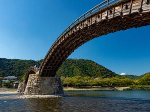 un puente sobre un cuerpo de agua con montañas en el fondo en KAMENOI HOTEL Setouchi Hikari, en Hikari