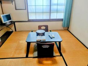 Kleines Zimmer mit einem Tisch und einem TV. in der Unterkunft Taiya Ryokan in Fuji