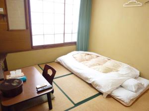 uma pequena cama num quarto com uma mesa e uma mesa sidx em Taiya Ryokan em Fuji