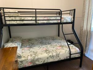 a twin bunk bed with a floral bedsheet and a desk at Fleur Cottage, 7 Willow Street in Crescent Head