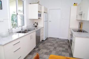 eine Küche mit weißen Schränken und einem Fliesenboden in der Unterkunft Fleur Cottage, 7 Willow Street in Crescent Head