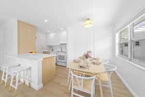 a white kitchen with a table and chairs and a counter at M Lake Worth Beach - Modern Apartments Near West Palm Beach in Lake Worth