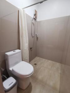 a bathroom with a white toilet and a shower at E&R Airport Hotel in Dumaguete